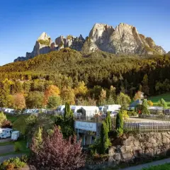 Malowniczy camping Seiser Alm z kamperami i przyczepami pod majestatycznymi szczytami Dolomitów.