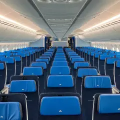 Puste rzędy siedzeń w kabinie samolotu Boeing 787-9. Błękitne zagłówki z logo KLM.