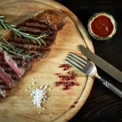 Succulenta bistecca di manzo, uno dei tanti tipi di bistecche di manzo, servita con rosmarino, sale grosso e pepe rosa.