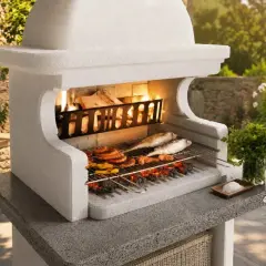 Una succulenta grigliata di pesce e carne cuoce su un barbecue in pietra, con fiamme vive e un contorno di erbe fresche.