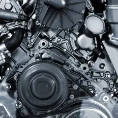 Detalle de un motor de motos 4 cilindros, con correas, poleas y componentes metálicos pulidos.