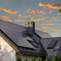 Dom z panelami fotowoltaicznymi na dachu, idealny do skorzystania z dotacji do fotowoltaiki. Zachód słońca z chmurami.