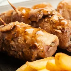 Roladki schabowe z pieczarkami duszone w sosie, podane z frytkami i groszkiem. Pyszne danie obiadowe.
