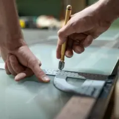 Ręce precyzyjnie tną materiał przypominający szkło, być może akryl. To co to za materiał, okaże się po obróbce.