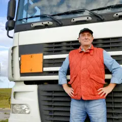 Kierowca ciężarówki przed chłodnym niebem. Może to być symbol kary za brak odpoczynku dobowego, gdy zmęczenie bierze górę.