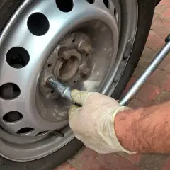 Main tenant utilise une clé pour changer un pneu.