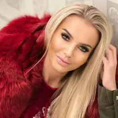 Monika Chwajoł w stylowej, czerwonej kurtce z futrem. Jej mąż z pewnością docenia jej modowy gust.