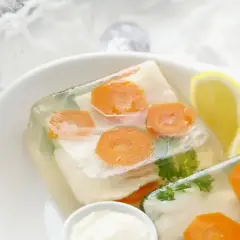 Elegancka ryba w galarecie z marchewką i natką pietruszki, podana z cytryną i chrzanem.