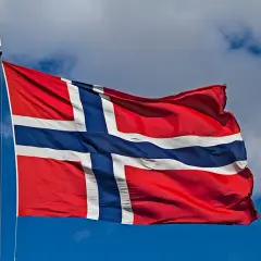Norwegia praca dla kobiet: flaga powiewa na tle błękitnego nieba z chmurami.