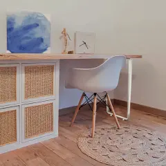 Bureau en pin relooké avec des portes en rotin. Une chaise blanche et un tapis rond complètent ce coin bureau moderne.