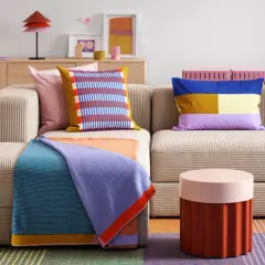 Gemütliches Wohnzimmer mit Sofa, bunten Kissen und Decken. Perfekt für die erste eigene Wohnung, um sich einzurichten.