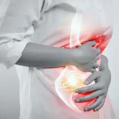 Persona con dolor de estómago, buscando cómo quitar el ardor de estómago.