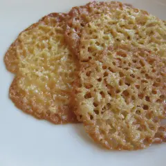 Tre gyllene havreflarn ligger på en vit tallrik. Dessa spröda kakor är perfekta för ett enkelt havreflarn recept.