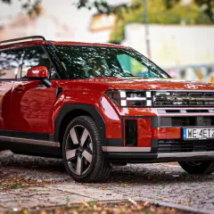Czerwony Hyundai Santa Fe 2025 z charakterystycznym przednim grillem i światłami, zaparkowany na brukowanej ulicy.