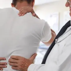 Lekarz bada pacjenta z bólem pleców. Może to być początek leczenia z aclexa.