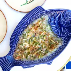 Un délicieux carpaccio de poisson servi dans un plat bleu en forme de poisson, parfait pour un déjeuner à Paris.