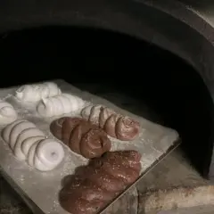 Des meringues blanches et chocolatées sont en cours de cuisson dans un four rustique.