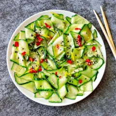 Insalata di cetrioli affettati sottili, condita con peperoncino, sesamo e scorza di limone. Un'idea fresca per le tue ricette con cetrioli.