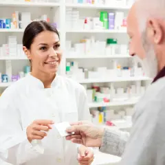 Farmaceutka podaje starszemu panu leki, doradzając mu atoris zamienniki.