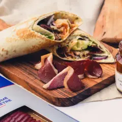 Wrap de magret de canard fumé, servi avec des tranches de canard et un confit d'oignons rouges.