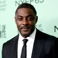 Idris Elba, znany z filmów, seriali i programów, w czarnym garniturze i krawacie.