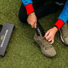 Un homme change la semelle intérieure de sa chaussure de sport sur un terrain artificiel.