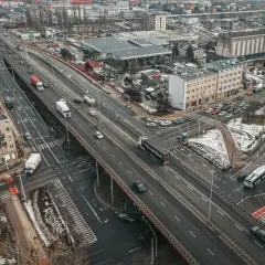 Widok z lotu ptaka na estakadę Kwiatkowskiego z ruchem samochodowym, budynkami i terenami zielonymi.