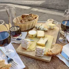Un plateau de fromages variés, du pain et du vin rouge, une scène qui raconte une belle histoire de la cuisine française.