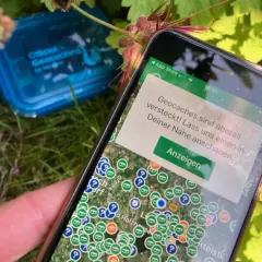 Smartfon pokazuje mapę z ukrytymi skarbami. To właśnie geocaching – zabawa w poszukiwanie skrytek z pomocą GPS.