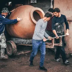 Mężczyźni przenoszą wielką glinianą qvevri, tradycyjny gruziński pojemnik do produkcji win.