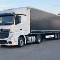 Biały Mercedes Actros MP4 z czarną plandeką naczepy Krone, gotowy do trasy.