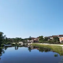 Tranquila playa fluvial en Leiro, con casas tradicionales reflejándose en el agua serena bajo un cielo azul.
