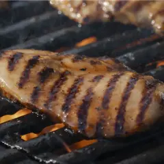 Saftig kycklingfilé med fina grillränder som grillas över öppen eld.