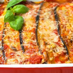 Berenjenas a la parmesana recién horneadas, burbujeantes y doradas, con queso fundido y un toque de albahaca fresca. ¡Un plato italiano irresistible!