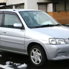 Srebrna Mazda Demio zaparkowana na mokrej nawierzchni ze śniegiem.