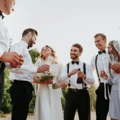 Radosne świadkowanie na ślubie. Para młoda z szampanem i kieliszkami w otoczeniu przyjaciół.