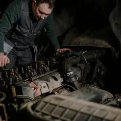 Mechanik w kamizelce pracuje nad silnikiem, wykonując odpowietrzanie silnika.