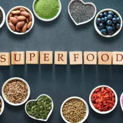 Scopri quali sono i superfood: semi di chia, mirtilli, mandorle, curcuma, zenzero, bacche di goji e altro ancora, disposti attorno alla parola "SUPERFOOD".