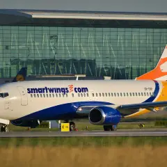 Samolot linii Smartwings z charakterystycznym malowaniem na tle nowoczesnego terminala lotniska.