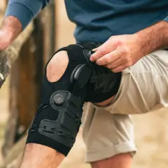 Mann legt eine DONJOY Schiene am Knie an. Die Schiene stützt das Bein für mehr Stabilität.