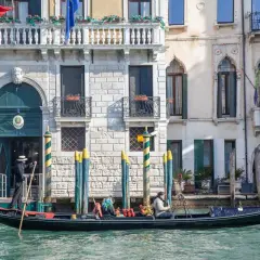 Gondola a Venezia, perfetta per un itinerario di un giorno. Un gondoliere guida la barca lungo un canale, con palazzi storici sullo sfondo.