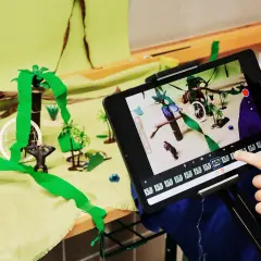 Kinder erstellen im Rahmen eines Stop Motion Projekts für die Grundschule eine Dschungelszene mit Spielzeugfiguren und bunten Kulissen.
