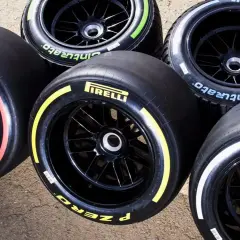Pięć opon F1 Pirelli P Zero z kolorowymi paskami: czerwonym, żółtym, białym, zielonym i niebieskim, gotowych na wyścig.