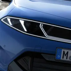 El frontal de un BMW azul eléctrico con tracción trasera, listo para devorar curvas en una carretera de montaña.