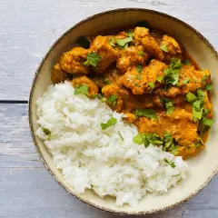 Aksamitny kurczak tikka masala w kremowym sosie, podany z puszystym ryżem i posypany świeżą kolendrą.