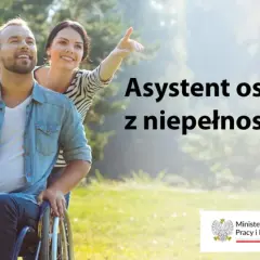 Uśmiechnięty mężczyzna na wózku inwalidzkim i kobieta wskazująca palcem w dal. Asystent osoby z niepełnosprawnością 2026.