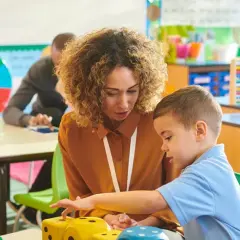 Lehrerin erklärt Kindern in der Schule Mathe mit Würfeln.