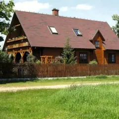 Drewniana zabudowa zagrodowa, idealna dla rolników, z werandą i drewnianym płotem.
