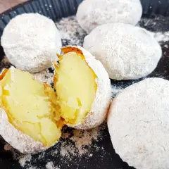 Pyszne ziemniaki z ogniska, upieczone w popiele, jeden przekrojony na pół, ukazujący miękki, żółty środek.