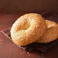 Deux bagels dorés, recouverts de graines de sésame, sur une serviette brune. Parfait pour une recette bagel moelleux.